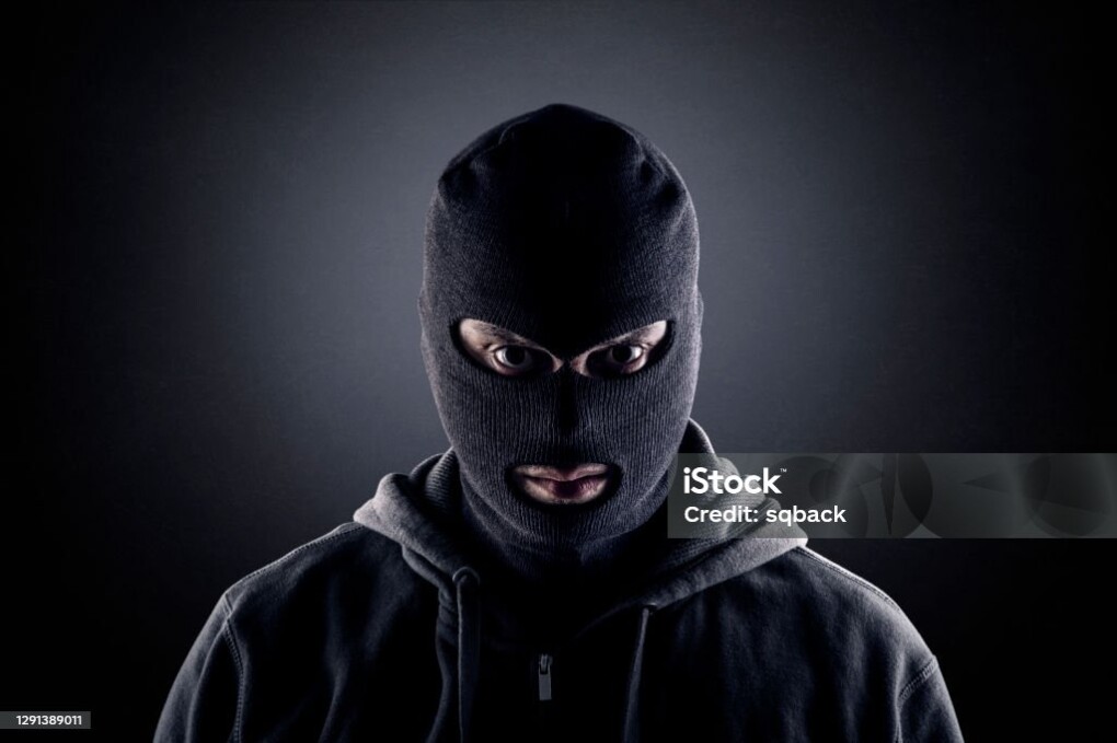 Criminal wearing black balaclava and hoodie in the dark