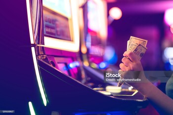 Slot Machine Play Time. Female Gambler Hand hold money bill ready to win the game with one best shot casino close up