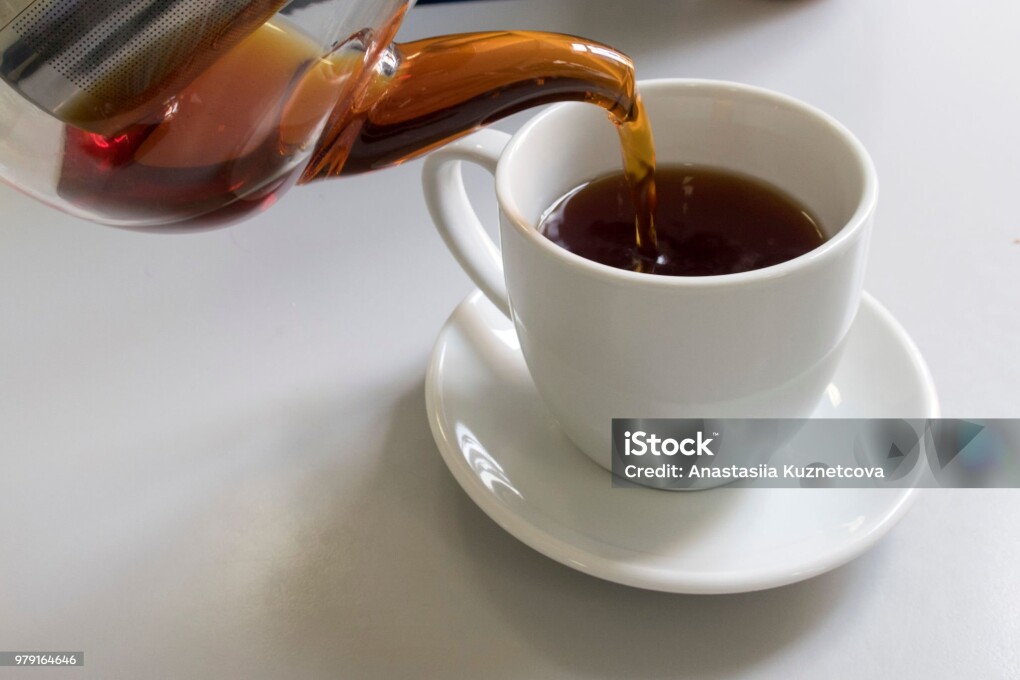 From a glass teapot tea pours into a mug