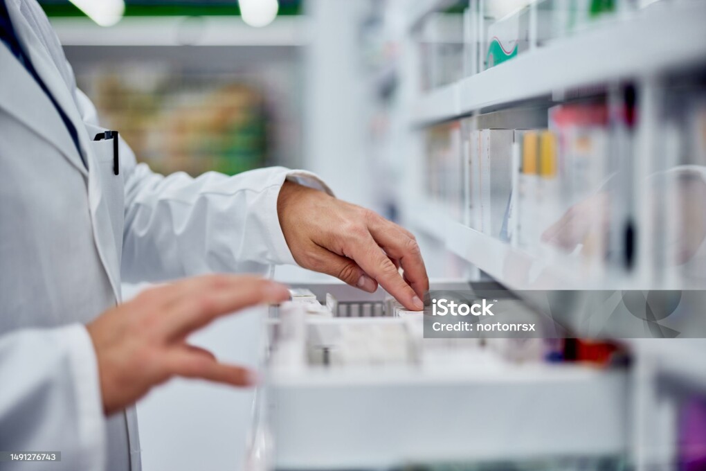 Male pharmacist choosing a medicine from the drawer, side view.