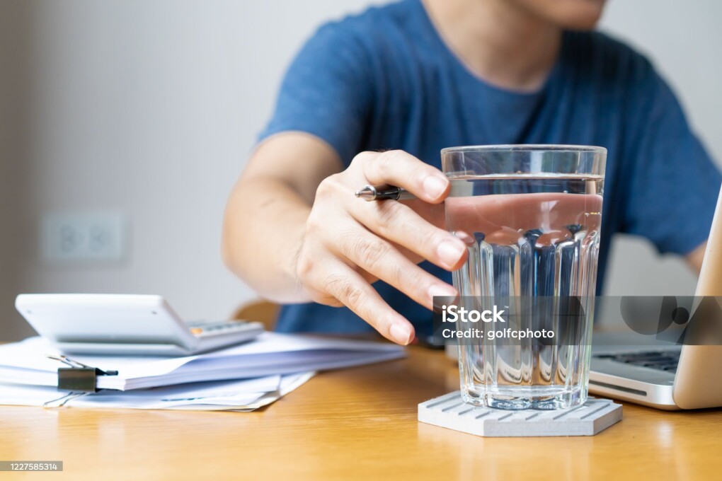 Businessman in relaxing casual working from home. Modern working lifestyle concept with copy space. Man drinking a mineral water in glass during working, refreshment during hard working.