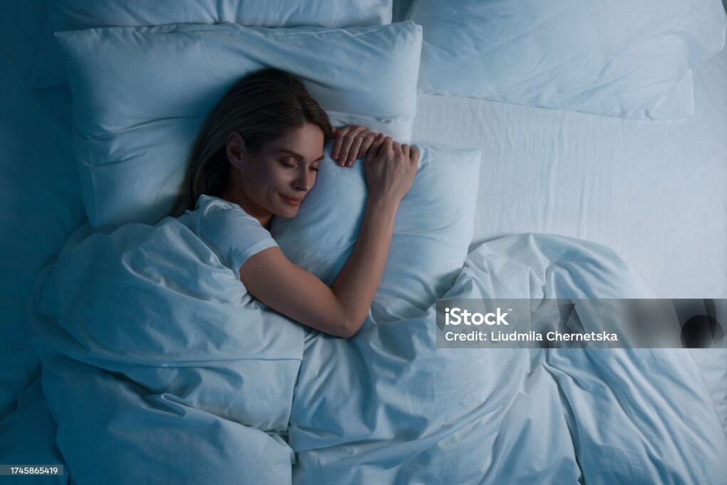 Woman sleeping in bed at night, above view. Space for text