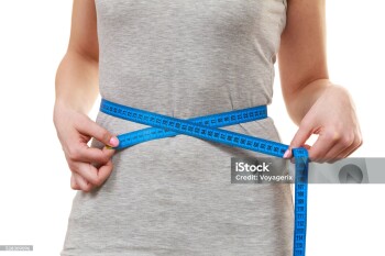 Woman fit girl measuring her waist with measure tape closeup. Part of female body isolated on white