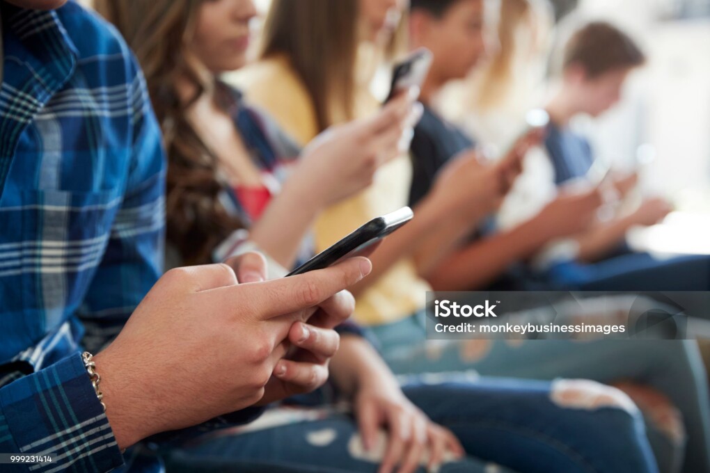 Close Up Of A Line Of High School Students Using Mobile Phones