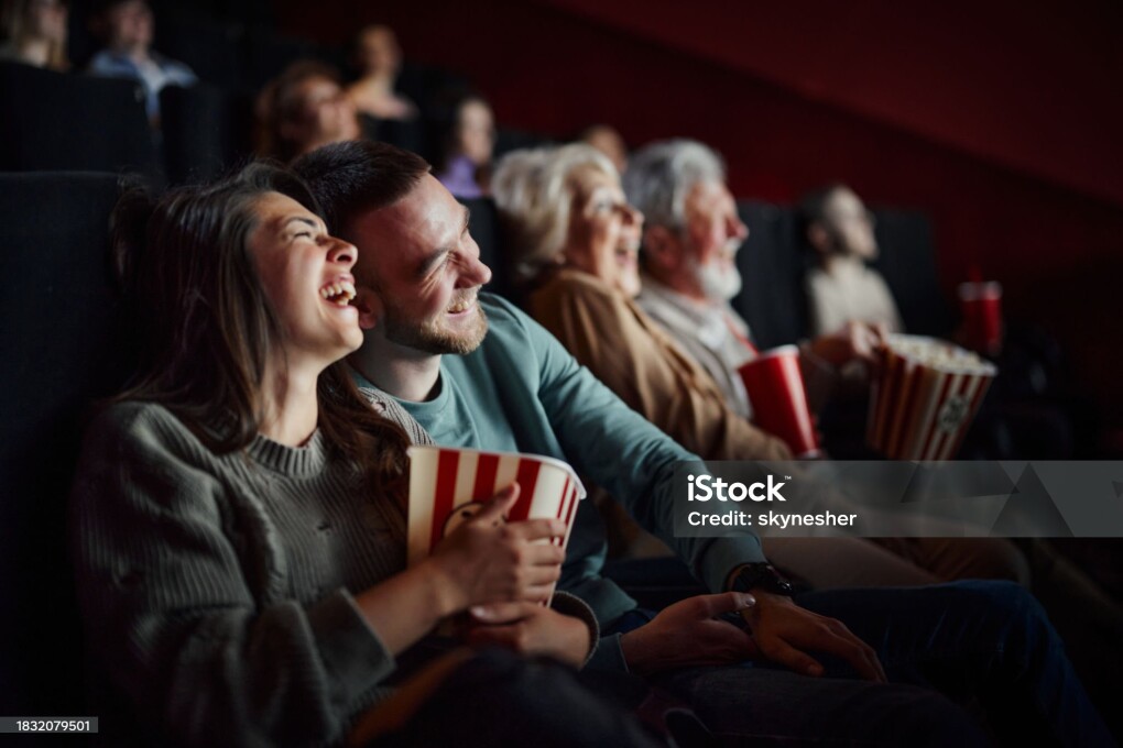 Cheerful couple having fun while laughing during a comedy movie in cinema.