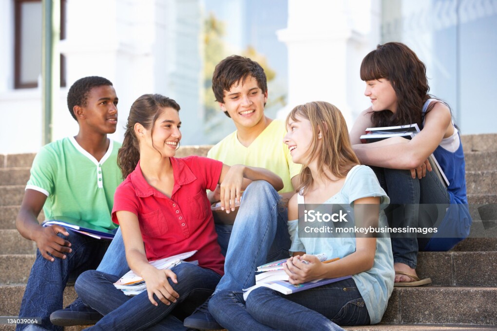 Group Of Teenage Friends Sitting On College Steps Outside