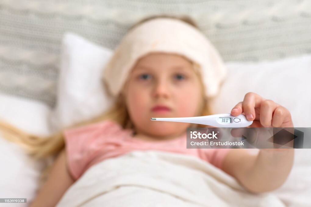 Sick little child girl lying in bed with thermometer. child shows a thermometer with high temperature