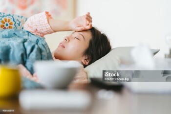 A women is feeling sick and sleeping on a sofa at home.