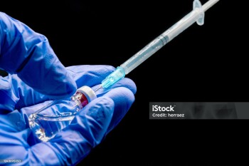 Close up of Doctor hands preparing the syringe and vial, for vaccination, on black isolated background.