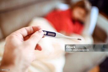Close up of thermometer with little girl in the background.