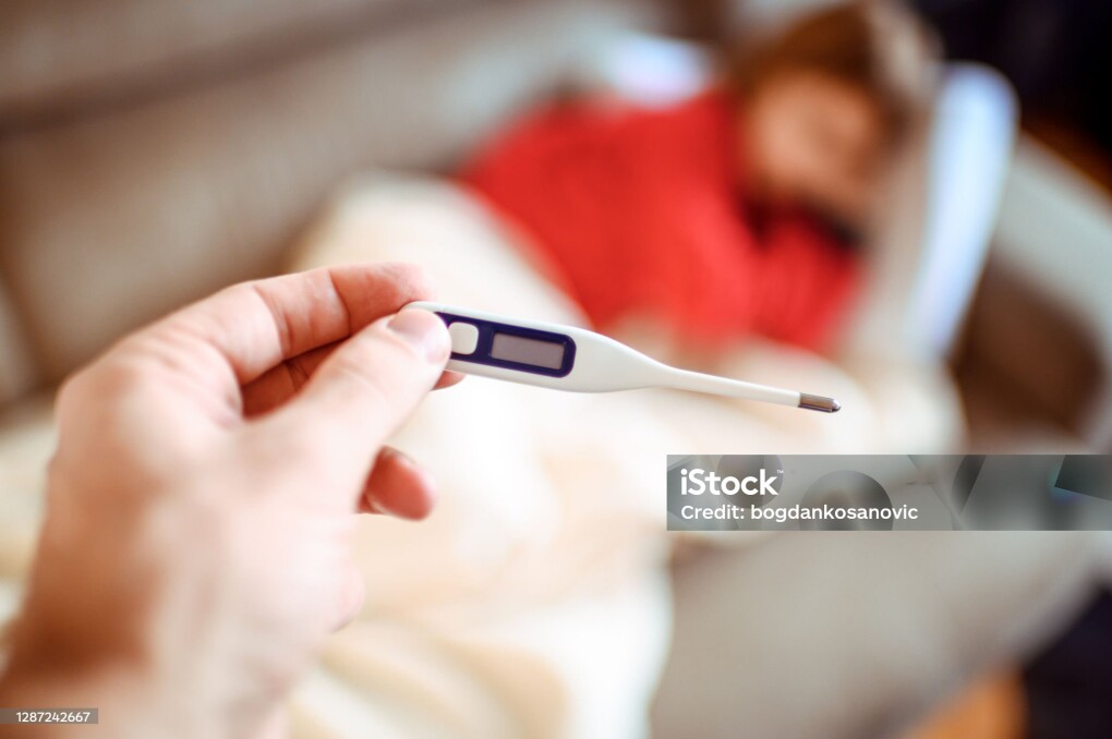 Close up of thermometer with little girl in the background.