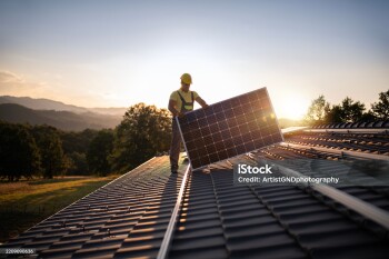 Shot Of Professional Workers Installing Solar Panels On A Roof At Sunset.