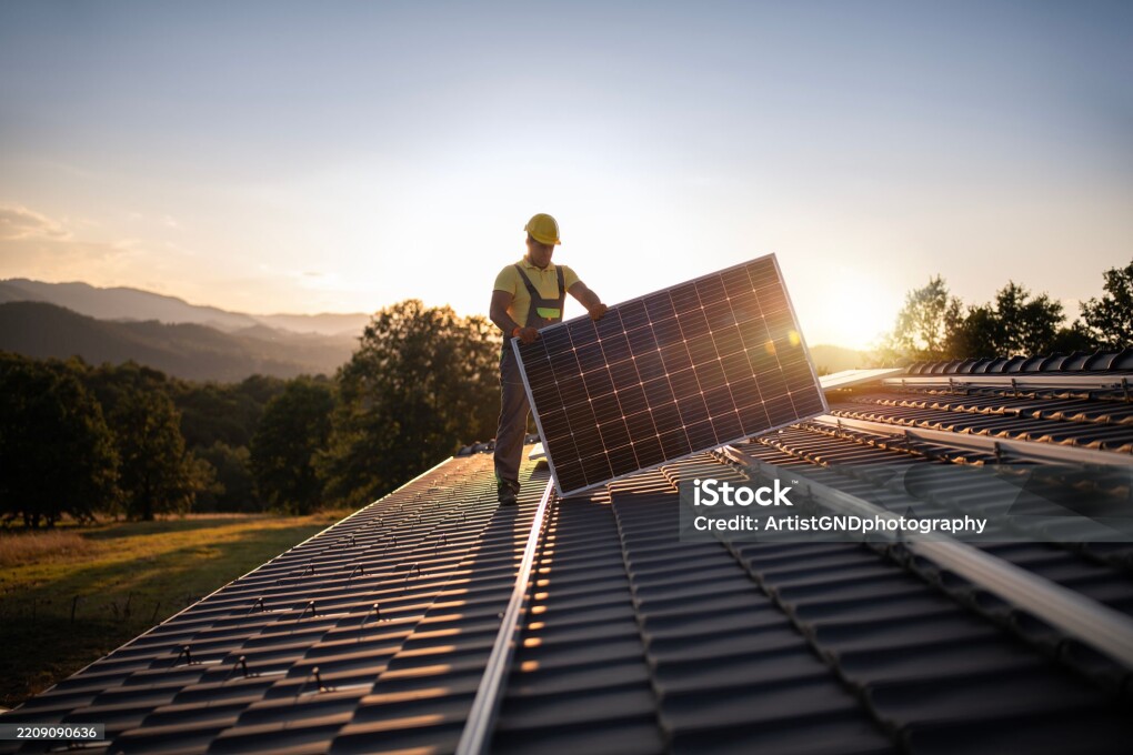 Shot Of Professional Workers Installing Solar Panels On A Roof At Sunset.