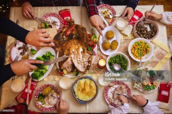 Family celebrates Christmas. At the dining table, the father carving stuffed roasted turkey and shares it with his family.