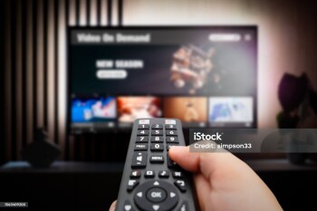 VOD service screen. Man watching TV with remote control in hand.