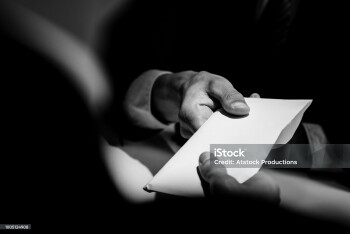 Businessman giving bribe money in the  envelope to partner in a corruption scam with black and white tone