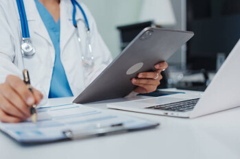 Asian female doctor is reviewing medical records, working on a computer, planning treatment, giving online consultations, and explaining medications to patients via a medical video call in a clinic