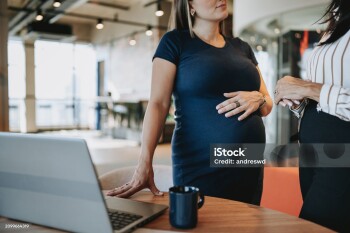 pregnant businesswoman talking to coworker