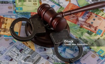 Handcuffs and bills of different denominations of the Kazakh currency tenge