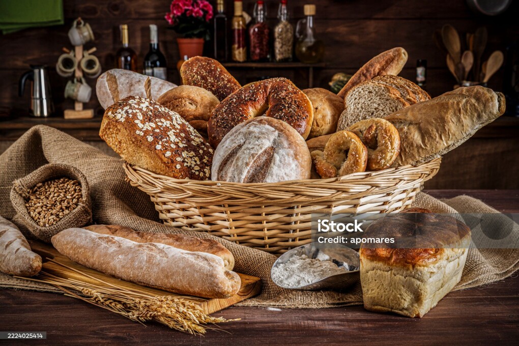 Artisanal bakery: Group of Fresh mixed breads, rolls and ingredients in a rustic kitchen.