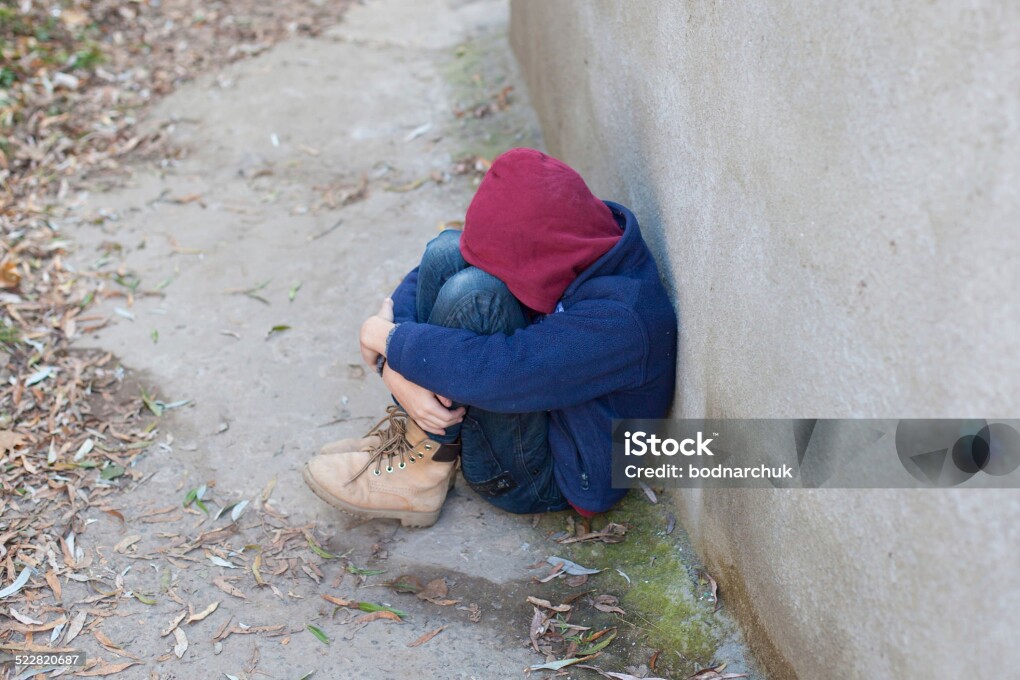 homeless young boy leaned against the wall