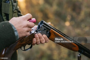 Hunter man loading his gun while hunting outdoors. Hunting season concept.