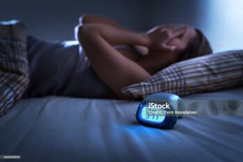 Sleepless woman suffering from insomnia, sleep apnea or stress. Tired and exhausted lady. Headache or migraine. Awake in the middle of the night. Frustrated person with problem. Alarm clock with time.