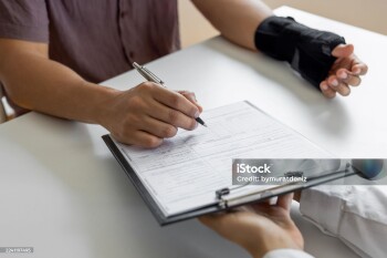 Unrecognizable man with broken arm filling form for insurance