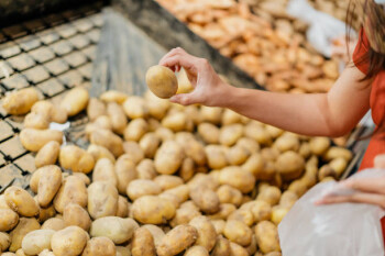Image of an Asian woman buying raw potatoes in supermarket