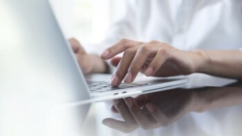 Close up of business woman hand typing on laptop computer keyboard with reflection on digital tablet on office table, online working, surfing the internet, distant job, remote work concept