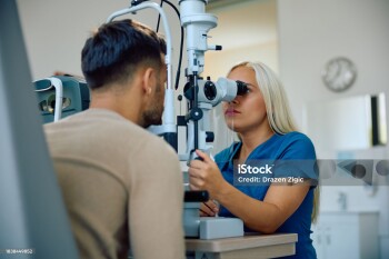 Ophthalmologist using diagnostic tool during eyesight check of a man at the clinic.