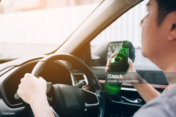 Asian men are breaking the traffic rules by holding a bottle of beer and drinking while driving.