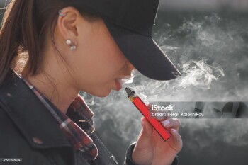 young girl smokes a vape close-up on a dark background, women smoke electronic cigarette in street