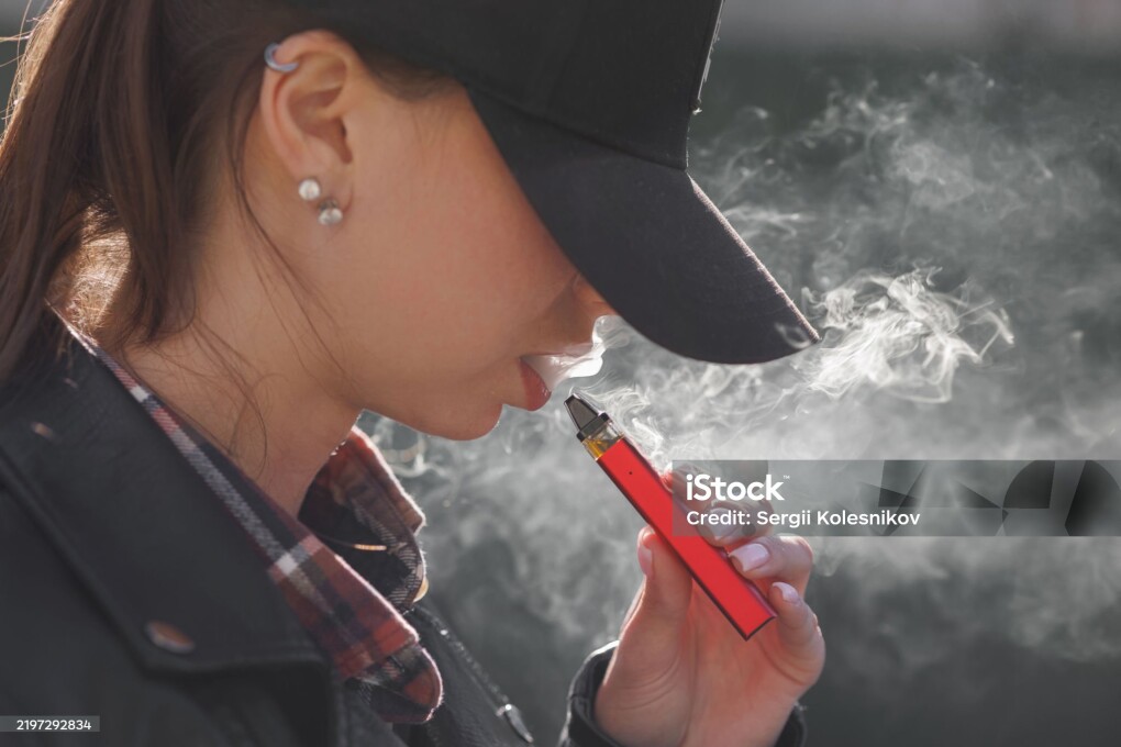 young girl smokes a vape close-up on a dark background, women smoke electronic cigarette in street