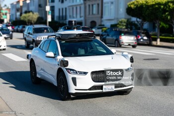 Waymo One Jaguar driverless autonomous car equipped with lidar sensors and cameras drives on a multi-lane city road. Front side view. Selective focus - San Francisco, California, USA - March 8, 2025