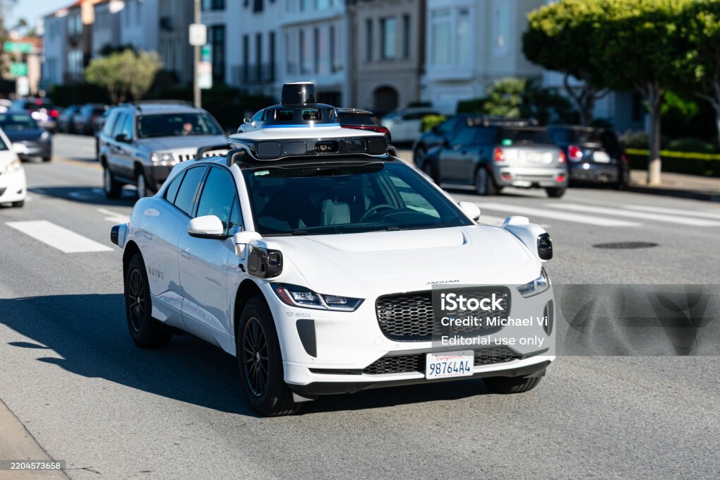 Waymo One Jaguar driverless autonomous car equipped with lidar sensors and cameras drives on a multi-lane city road. Front side view. Selective focus - San Francisco, California, USA - March 8, 2025