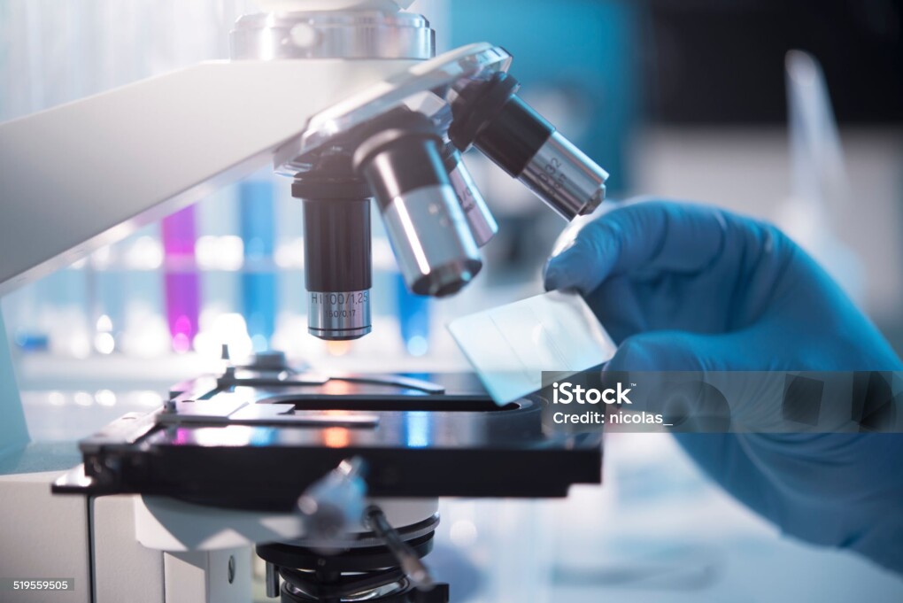 A scientist placing a slide under a microscope