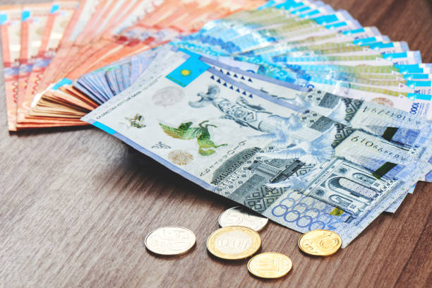 Tenge. Kazakh money is spread out on a brown wooden table close-up."n