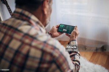 Elderly man uses smartphone for sports betting from home