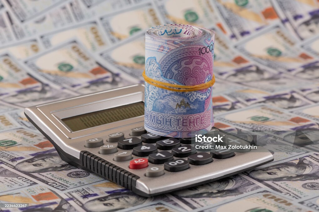 Banknotes of 10,000 Kazakhstani tenge and calculator against the background of 100 US dollar bills