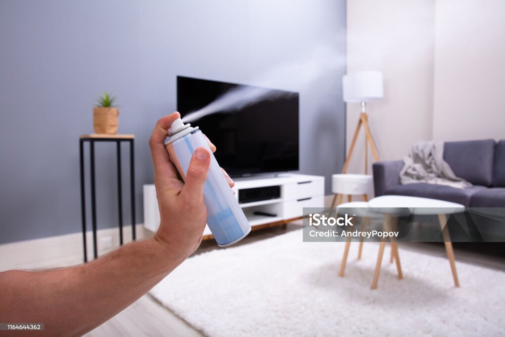 Close-up Of A Person's Hand Spraying Air Freshener In Living Room