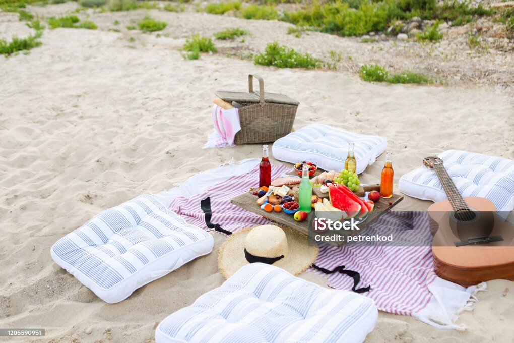 Picnic on the beach at sunset in the style of boho. Food and drink, relax, holiday concept