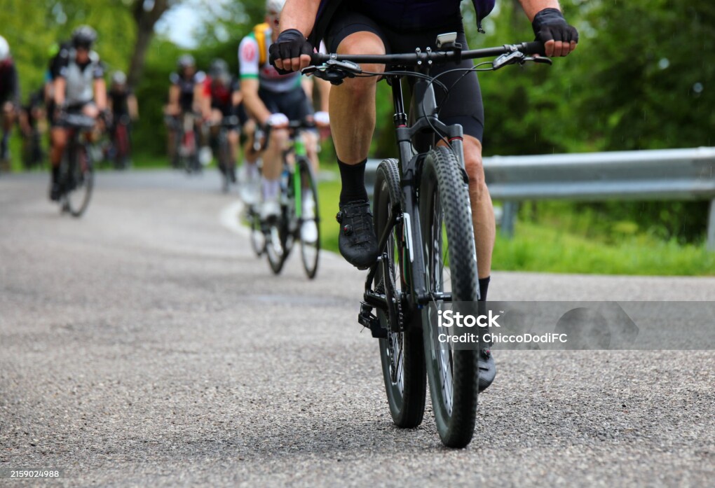 Gravel bike racing on mixed terrain with other cyclists in the background