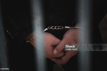 Male hands in handcuffs black background. a handcuffed prisoner in a prison or courtroom.