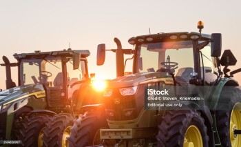 Kingsville, Ontario, Canada - July 27, 2024:   Two John Deere farm Tractors silhouetted against the setting sun.