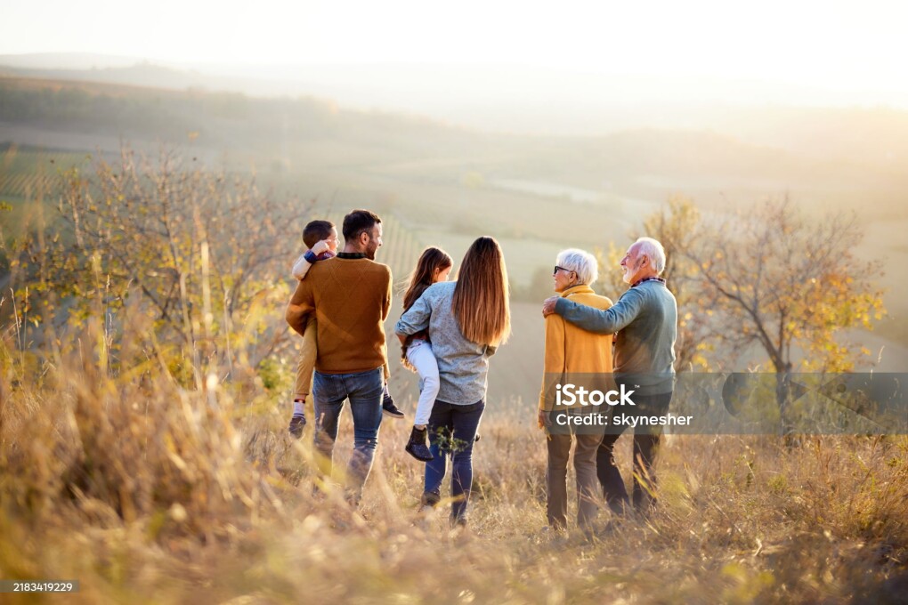 Rear view of extended family communicating while taking a walk in autumn day on a hill. Copy space.