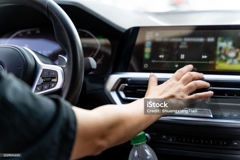 Hands operating the car's center console and touching the LCD screen, combined with the car's streamlined interior layout, create a practical and convenient driving scene. The image focuses on hand movements interacting with the car's in-car interface, conveying a sense of intelligent car technology. This image is suitable for themes such as automotive technology, in-car systems, and driving life, and details of human-vehicle interaction, adding a sense of realism to car-related content.