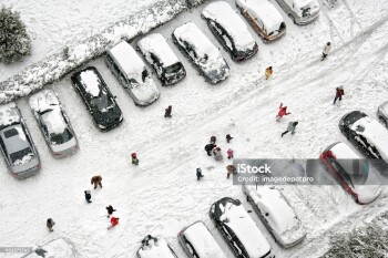 Elevated view of children play in snow covered parking lot