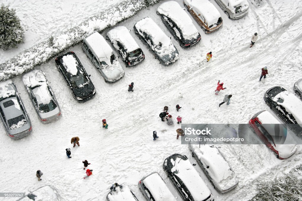 Elevated view of children play in snow covered parking lot