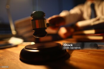 Focus on judge utility on wooden table used to maintain order and pronounce a verdict in courtroom in front of many people. Rule of law and strict court concept
